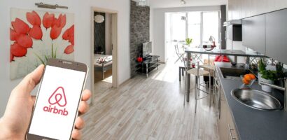 Person holding phone with AirBnB app in condo living area