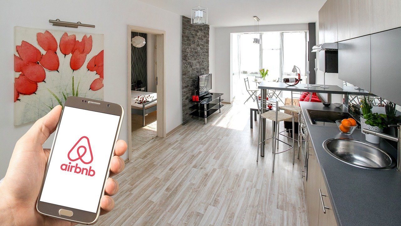 Person holding phone with AirBnB app in condo living area