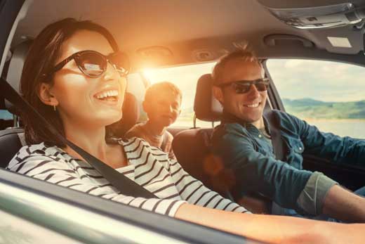 Man, woman, and child driving in a sunny vehicle