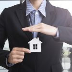 man-in-a-suit-holding-a-small-house