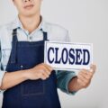 business owner holds closed sign