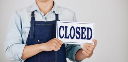 business owner holds closed sign