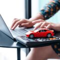 woman types on laptop with model car on desk