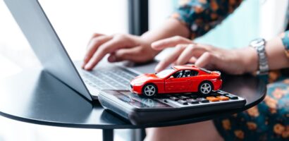 woman types on laptop with model car on desk