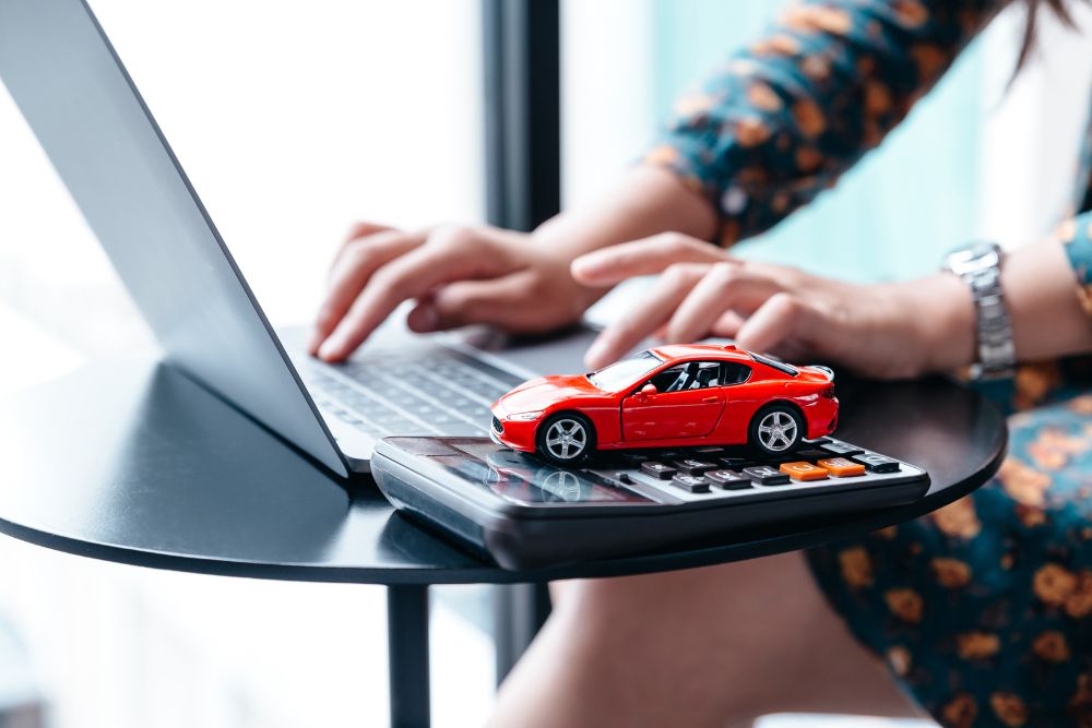 woman types on laptop with model car on desk