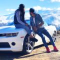 couples on white sports car by a snow covered mountainside