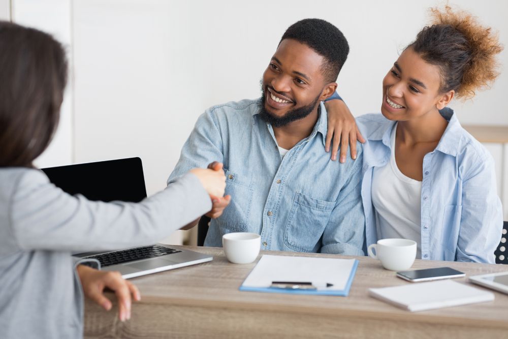 young couple shakes hands with insurance broker