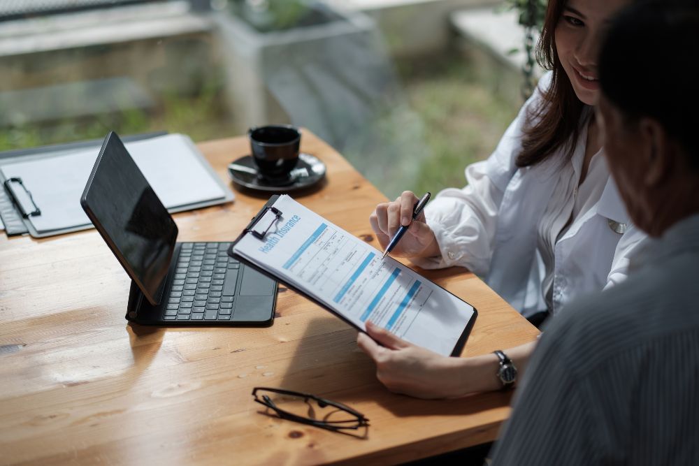 woman sits at laptop looking over insurance information