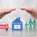 insurance broker's hands protect cut outs of car, home, and family