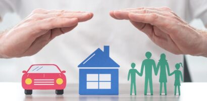 insurance broker's hands protect cut outs of car, home, and family