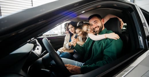 Family smiling and hugging inside a car during a drive