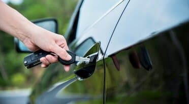 Hand unlocking a car door with a key fob