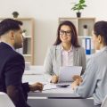 couple meets with female insurance broker, sitting at desk