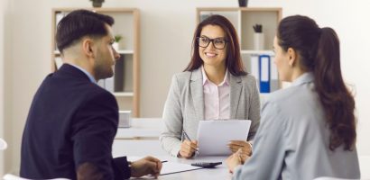 couple meets with female insurance broker, sitting at desk