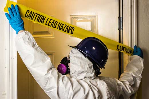 person in hazmat suit covers doorway with warning tape