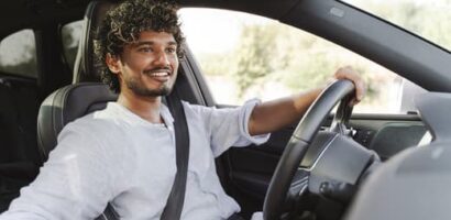 Man smiling while driving a car on a sunny day