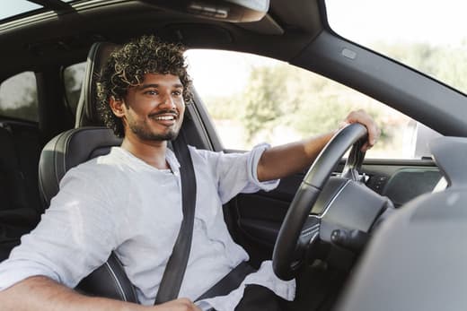 Man smiling while driving a car on a sunny day