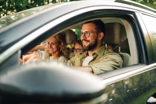 Man driving car with passengers smiling during a road trip