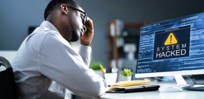 man upset in front of computer that shows system hacked message