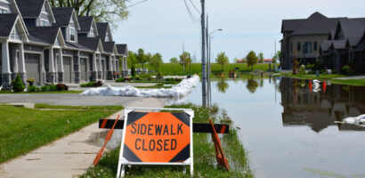 Orange sidewalk closed sign in front of flooded street