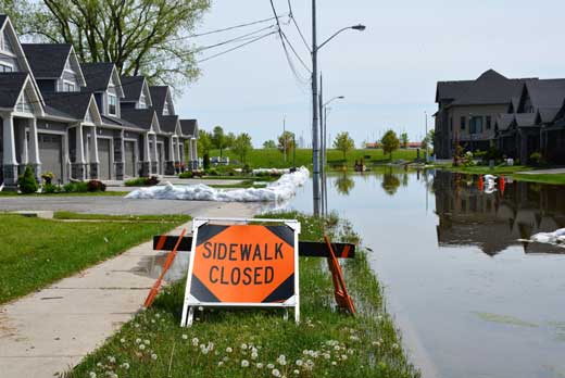 Orange sidewalk closed sign in front of flooded street