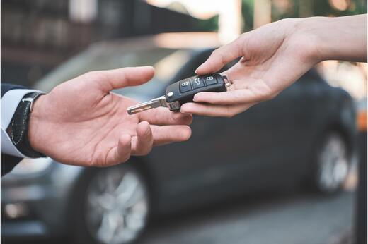 Close-up of one person handing car keys to another