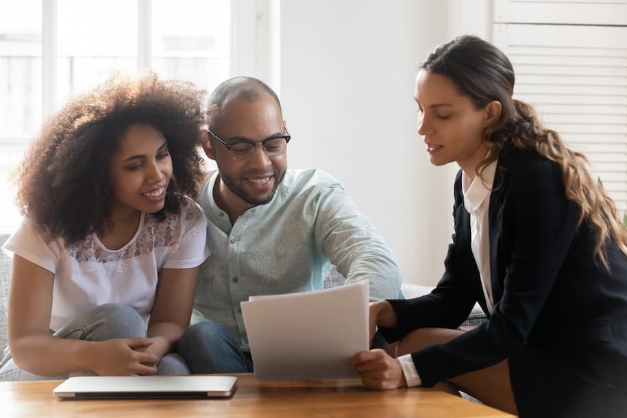 professional woman showing paper to happy black couple