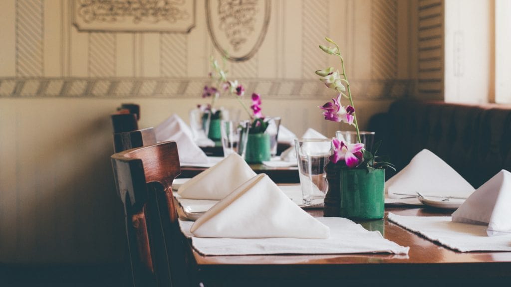 purplue-flowers-and-napkins-sitting-on-a-wooden-restuant-table