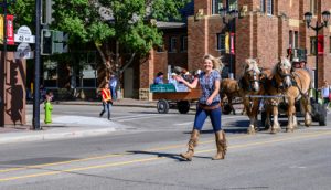 Blonde woman wearing tassled boots walks down road during parade in Red Deer, Alberta