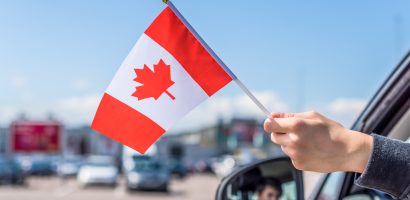 Person hanging a Canadian flag out of a car window