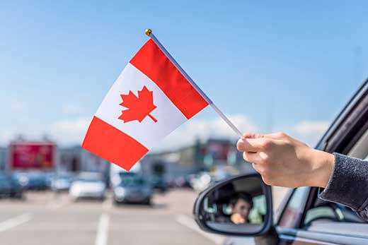 Person hanging a Canadian flag out of a car window