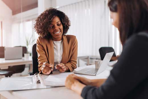 Two people meeting at a desk discussing car insurnace