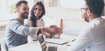 Three people sitting at a table shaking hands