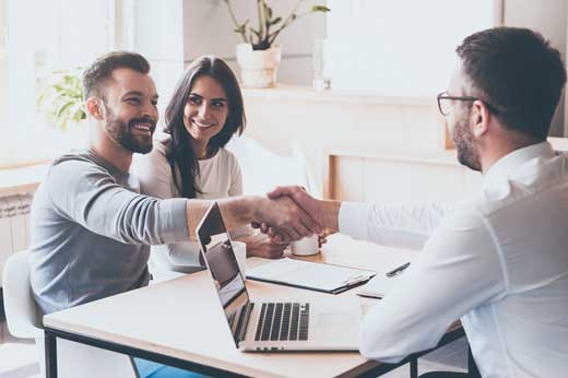 Three people sitting at a table shaking hands