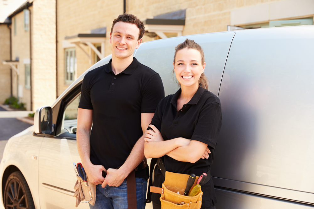 Portrait of male and female trade workers by a van