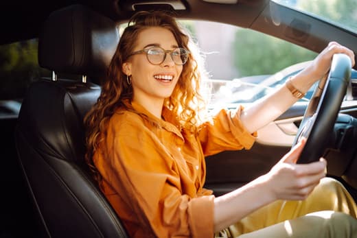 Woman smiling while driving car in daylight