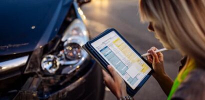 Woman documenting car damage on a tablet after a collision