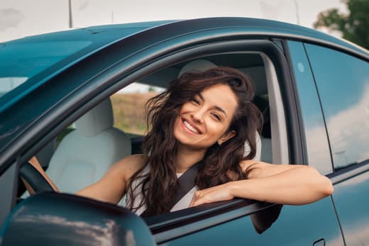 Smiling woman leaning out of car window while driving